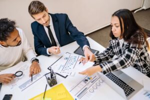 Personas analizando datos en dispositivos electrónicos en una oficina moderna, iluminada por luz natural.